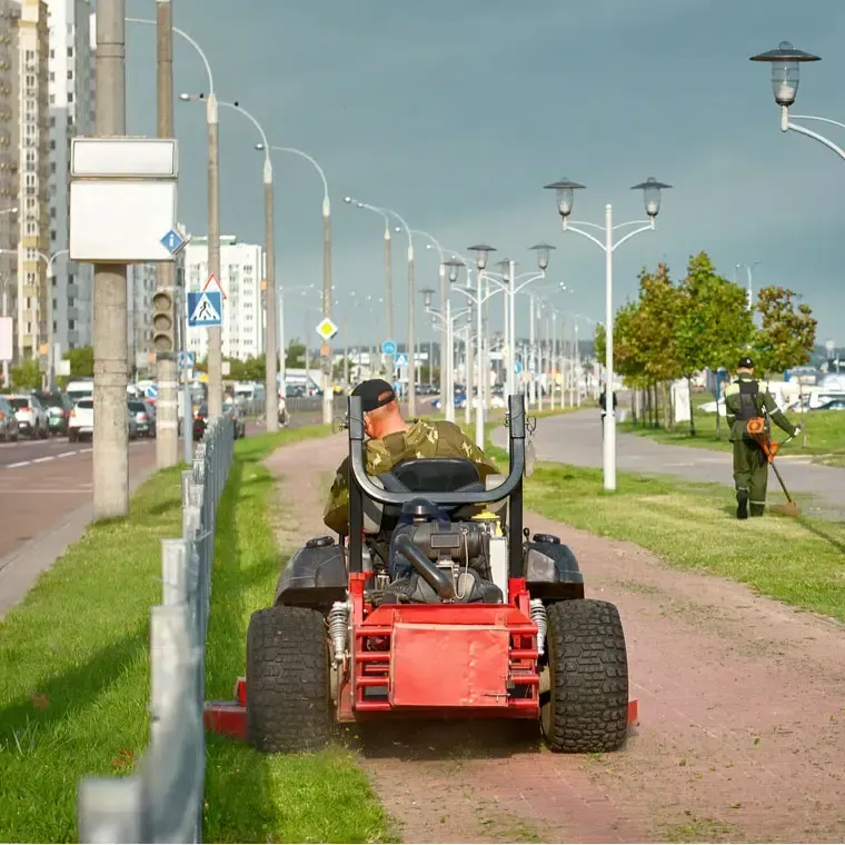 Ride-on mower maintaining grass beside a landscaped path