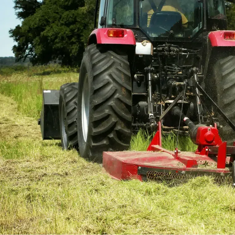 Tractor with a slashing attachment cutting long grass